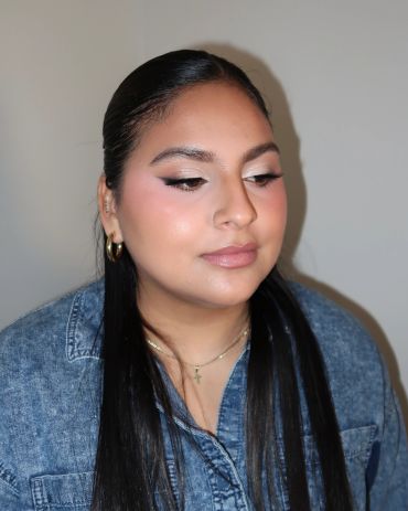 Woman with sleek hair and natural makeup wearing a denim shirt.