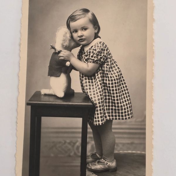 Vintage photo of a toddler with a doll on a table.