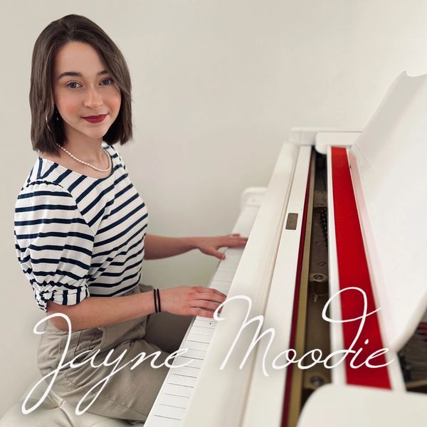 Young woman playing a white piano, smiling at the camera.