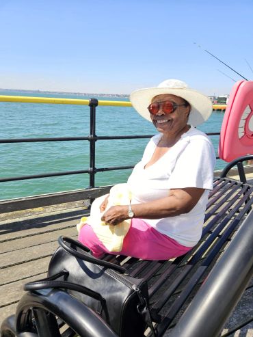 Smiling woman sitting on a bench by the water.