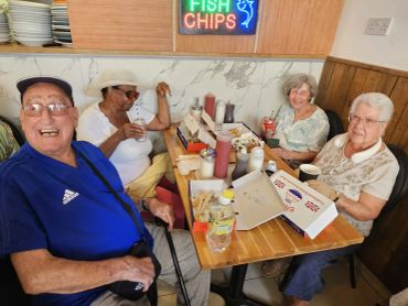 Four elderly friends enjoying a meal at a fish and chips shop.