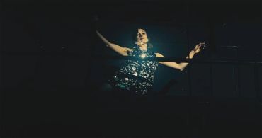 Person dancing in a dark, spotlight-lit setting.