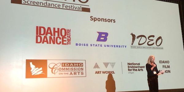 Speaker at a Screendance Festival with sponsor logos.