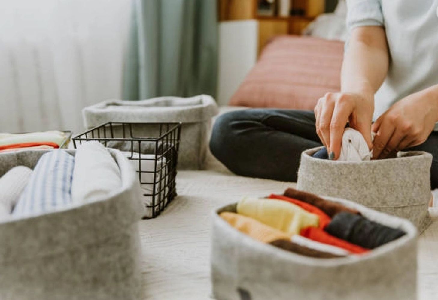 Organizing clothes into fabric storage bins on a bed.