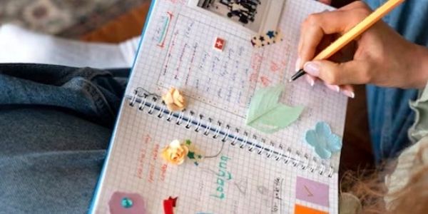Person writing in a decorated notebook.