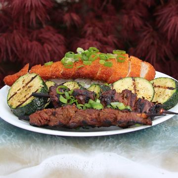 Grilled meat, zucchini, and fish on a plate.
