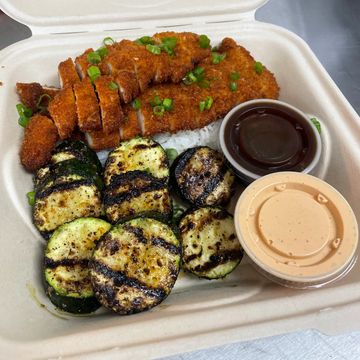 Grilled zucchini, breaded chicken with sauces in a takeout container.