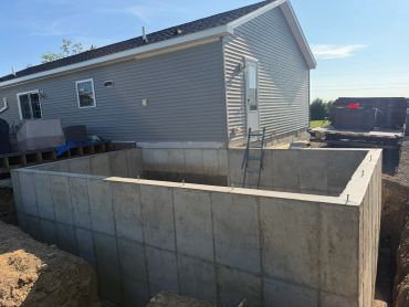 Concrete foundation near a residential house under construction.
