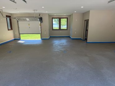 Empty garage with a gray floor and open door.