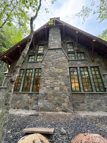 Stone house with green window frames in forest.