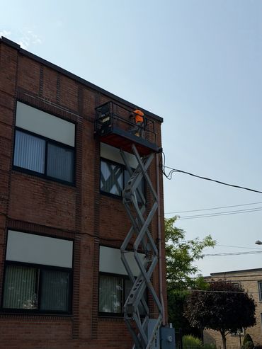 Worker on scissor lift fixing building exterior.