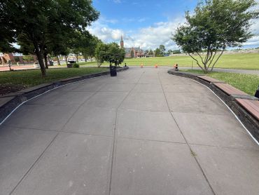 Empty paved pathway in a park under blue sky.