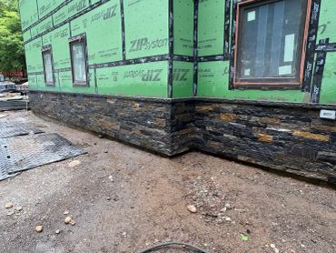 Newly constructed house with stone siding on the lower portion.