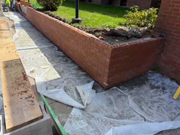 Newly constructed brick wall with protective covering on the pavement.
