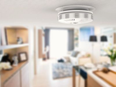 A smoke detector installed on a ceiling in a modern living room.