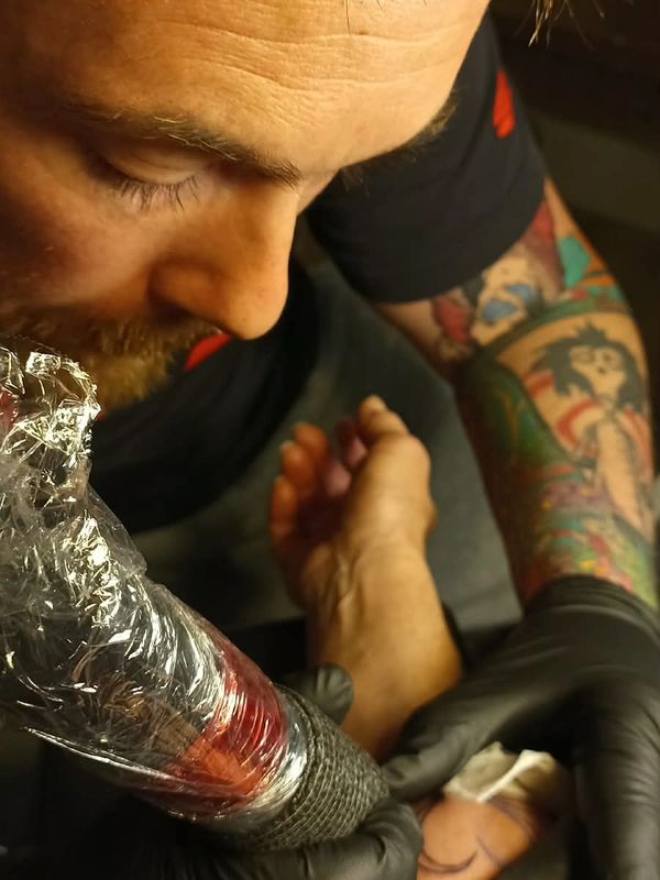 Tattoo artist working on a forearm tattoo.