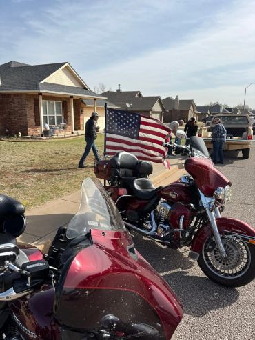 Two red motorcycles with an American flag parked in a suburban neighborhood.