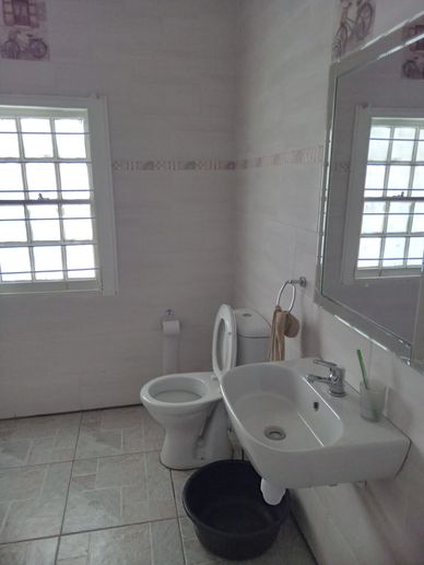 Simple bathroom with a toilet, sink, mirror, and window.
