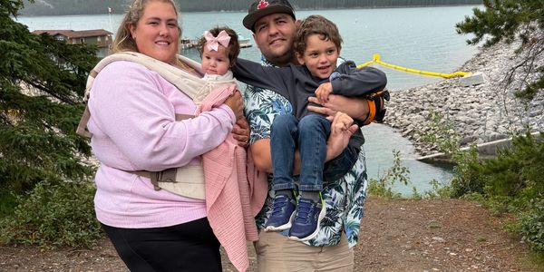 Family posing outdoors near a lake.