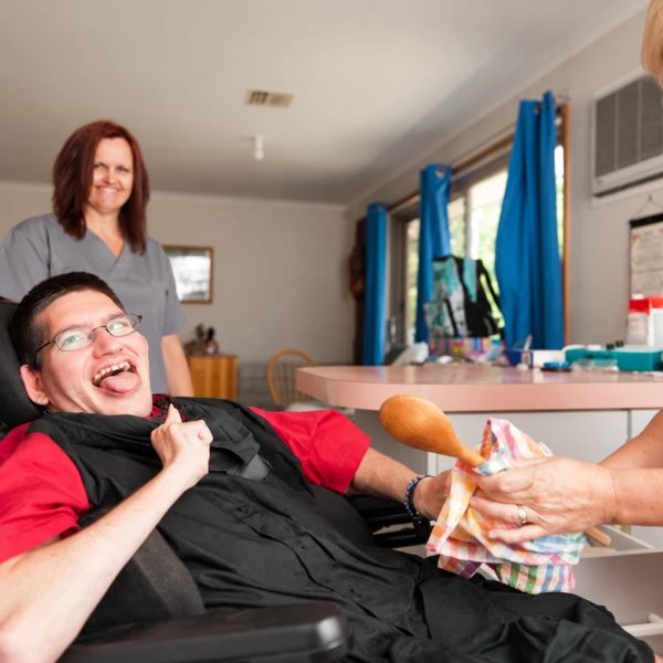 Man in wheelchair laughing with two caregivers.