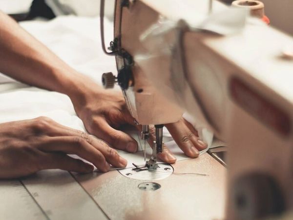 Woman sews behind sewing machine at work
