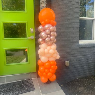 Orange and peach balloon arrangement by a bright green door.