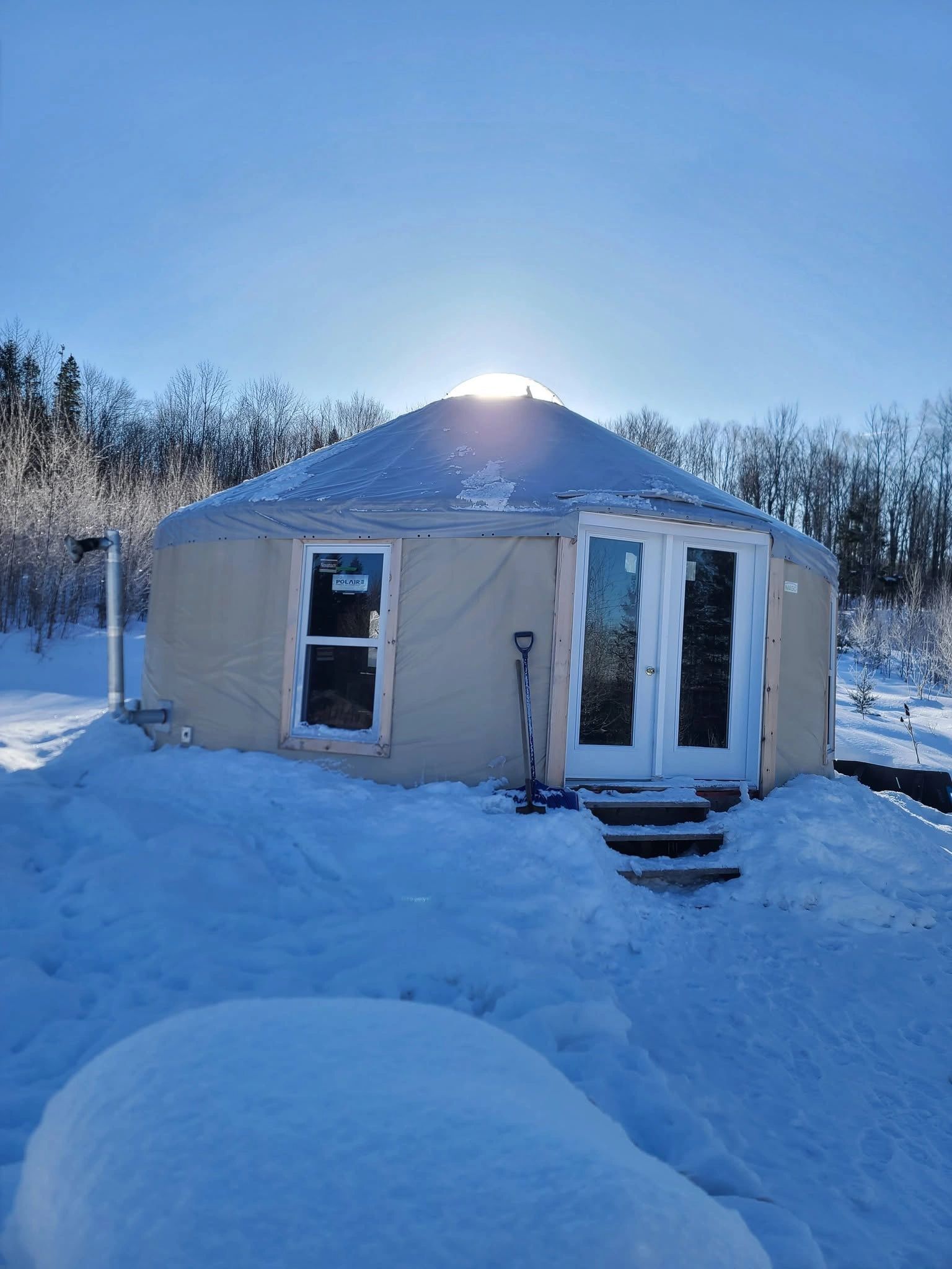 A round yurt covered in snow under a clear blue sky.
