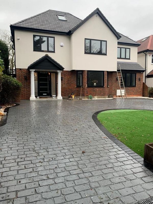 Modern two-story house with a large driveway and artificial grass lawn.