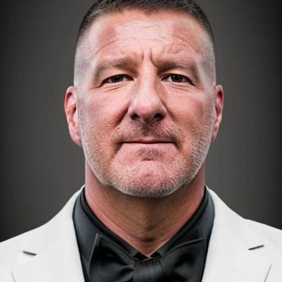 Portrait of a confident man in a white suit jacket and black shirt.