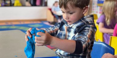 A boy playing with blue slime in a classroom.