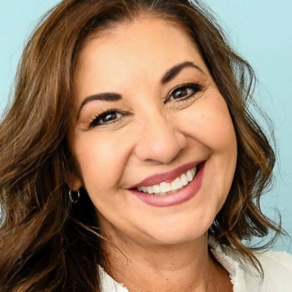 Smiling woman with brown hair and hoop earrings.