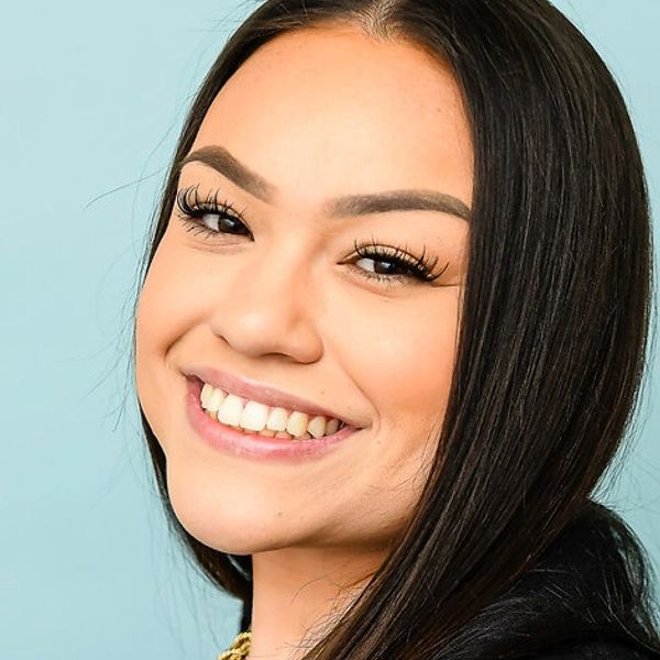 Young woman with a bright smile against a blue background.