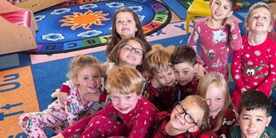 Group of children smiling on a colorful carpet.
