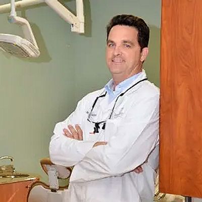 Dr. Mark McCoy, DMD poses by his dentist chair, ready to help!