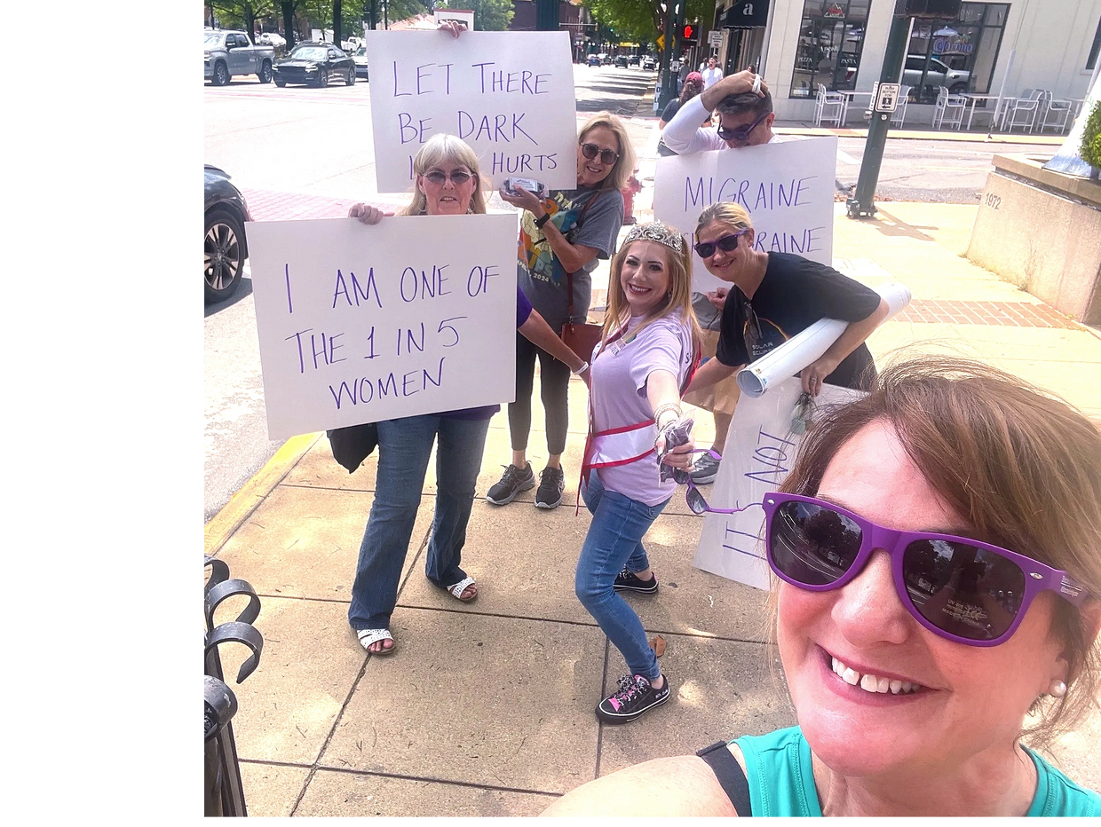 Group of women holding signs raising awareness about migraine and light sensitivity.