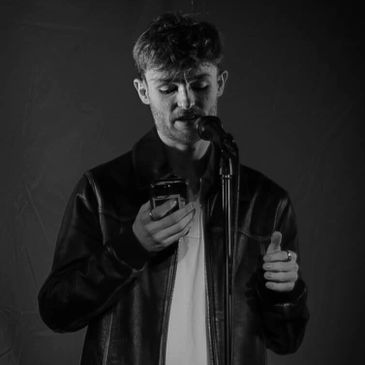 Man reading from phone while speaking into a microphone in black and white.