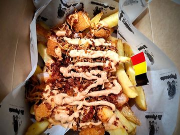 Papas compuestas con trozos de pollo, tocino crujiente y salsa