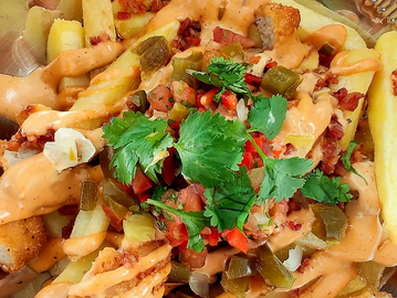 Papas compuestas con trozos de pollo, pico de gallo y salsa