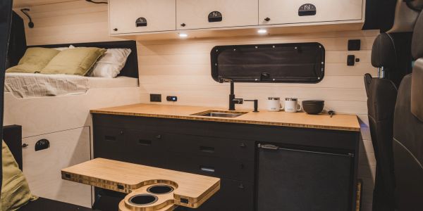 Cuisine compacte et lit dans une van aménagée.