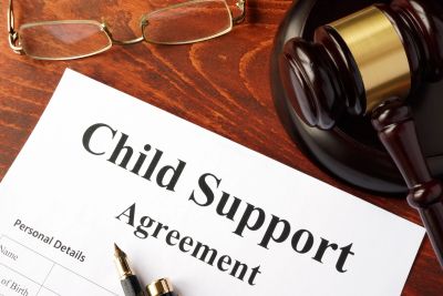 A child support agreement document with a gavel and glasses on a wooden table.
