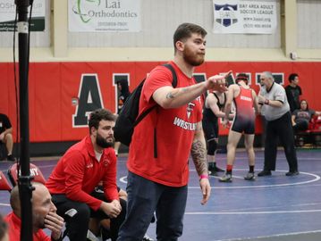Coach giving instructions during a wrestling match at Albany gymnasium.