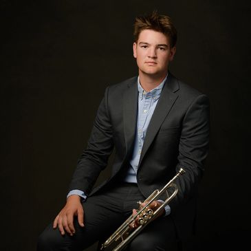 high school senior portrait of a young man holding a trumpet