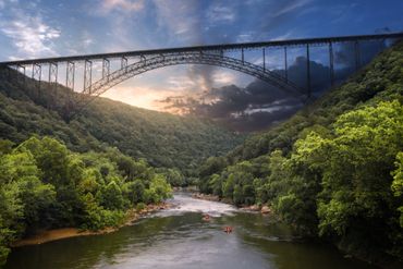 Sunset over the New River Gorge Bridge, with two whitewater rafts.
