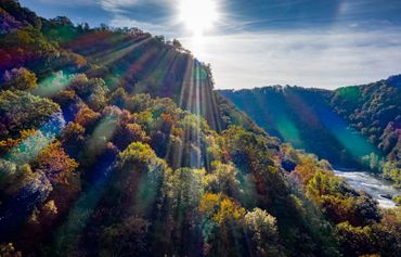 Sunrise over a cliff with brightly colored lens flares.