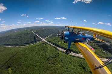 A bi-plane flies over the New River Gorge Bridge.