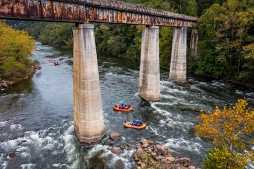 Two orange rafts under an old railroad bridge.