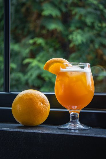 An orange drink in front of green trees.