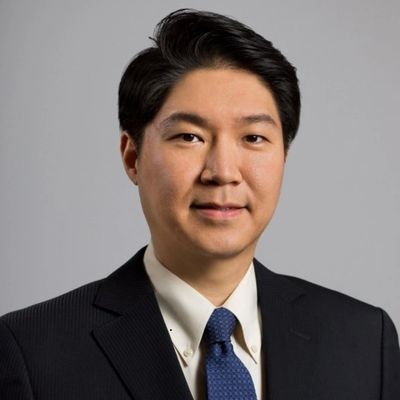 Professional headshot of a man in a suit and blue tie.