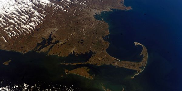 Aerial view of Cape Cod and surrounding areas with ocean and clouds.