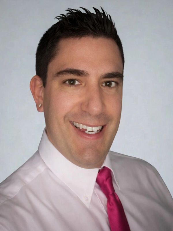 Smiling man in white shirt and bright pink tie.